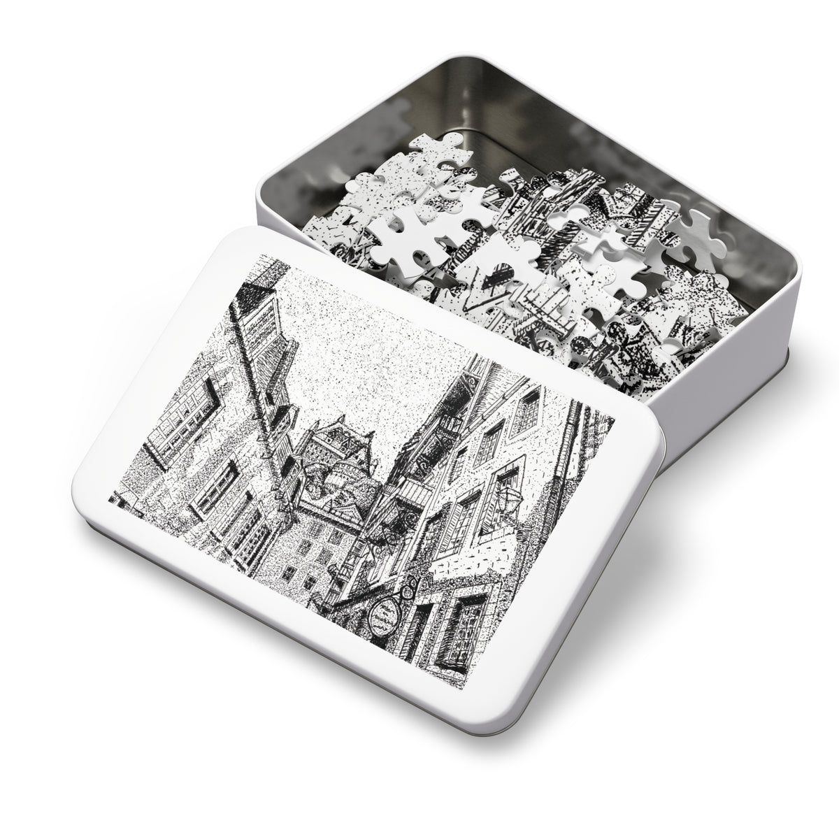 An open rectangular metal jigsaw puzzle box showing white puzzle pieces inside, with the lid displaying a black-and-white architectural illustration on a clean white background.
