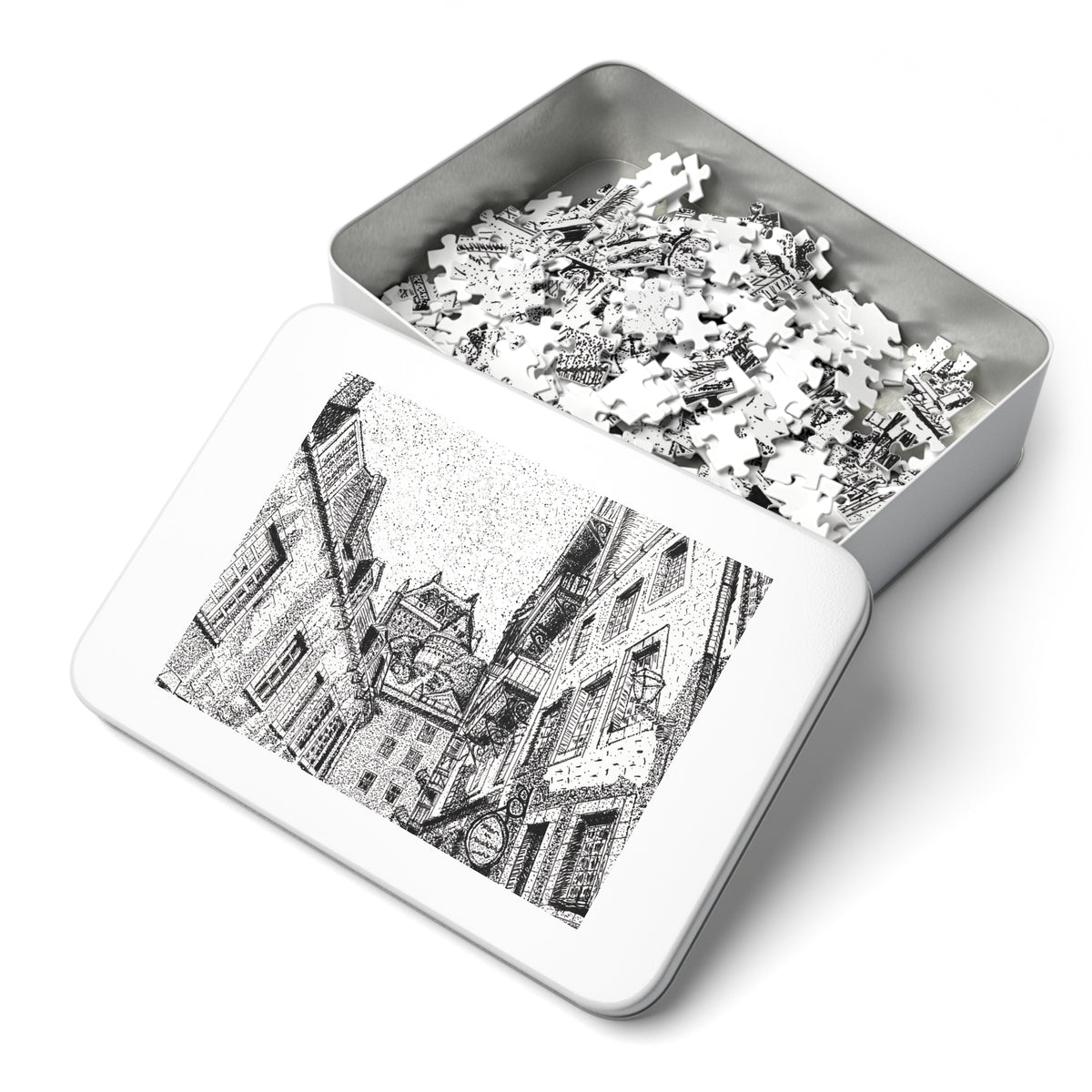 An open rectangular metal jigsaw puzzle box showing white puzzle pieces inside, with the lid displaying a black-and-white architectural illustration on a clean white background.
