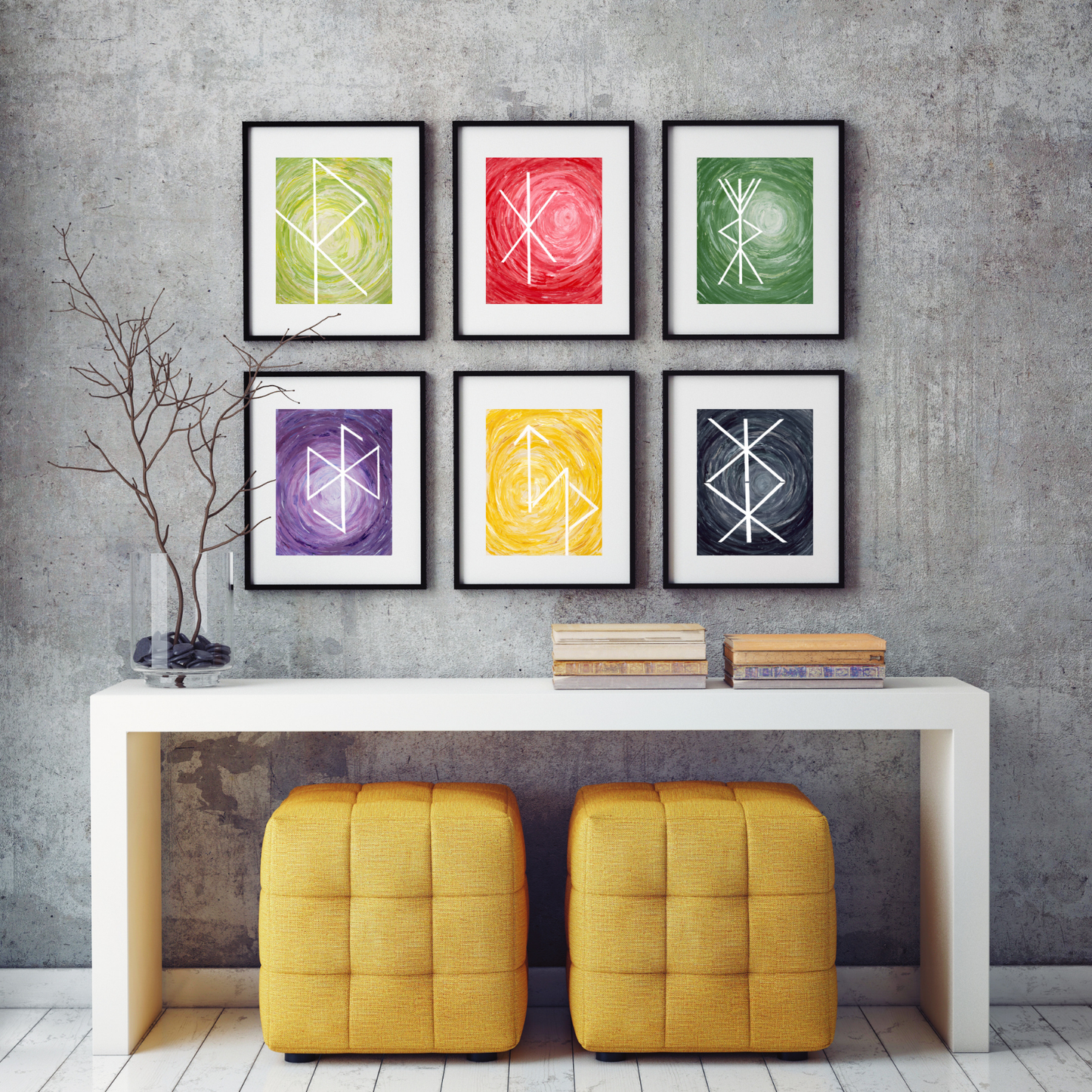 Six framed abstract art prints with white geometric Bind Rune symbols in green, red, green, purple, yellow, and black, displayed on a gray concrete wall above a white console table with two yellow ottomans.